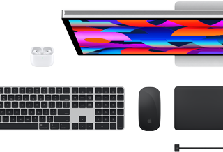 Vista de cima dos acessórios Mac: Studio Display, AirPods, Magic Keyboard, Magic Mouse e Magic Trackpad