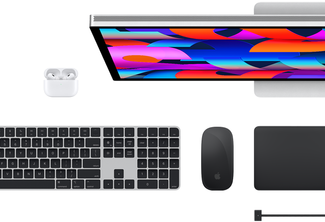Vista de cima de alguns acessórios Mac: Studio Display, Magic Keyboard, Magic Mouse, Magic Trackpad, AirPods e cabo de carregamento MagSafe
