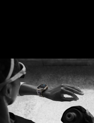 Atleta a olhar para o Apple Watch Ultra 2 no pulso esquerdo e a fazer o gesto de duplo toque com o indicador e o polegar da mão esquerda