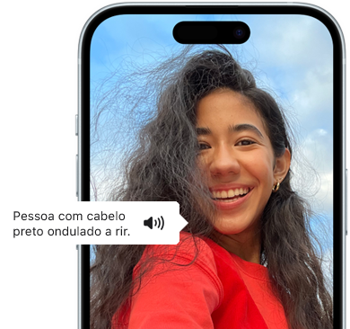 iPhone 15 a mostrar a funcionalidade VoiceOver a anunciar informações sobre a imagem e uma pessoa com cabelo preto ondulado a rir